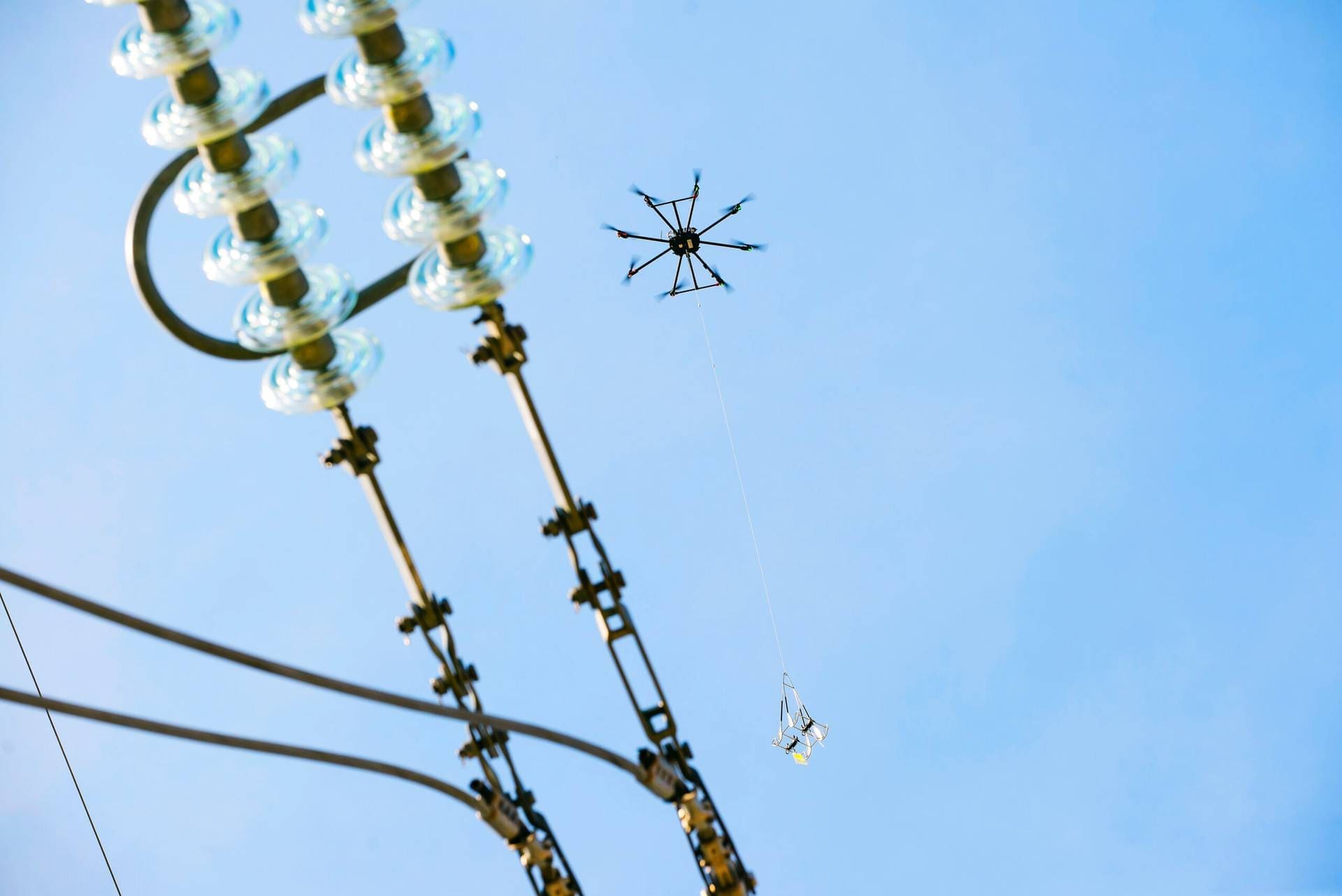 Eine Drohne hängt Vogelschutzmarkierungen vom Typ FireFly an eine unter Spannung stehende 110-kV-Leitung – el.demo.weblegend.pl